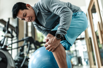 A man use pilates ball and hurt knee at gym. Fitness, gym, workout and lifestyle concept.