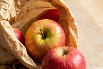Apples, Pink Lady variety, in a brown paper bag on a wood background.  Environmentally friendly packaging concept