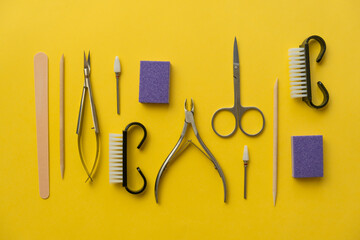 Professional manicure tools on yellow background. Manicure set. Top view. Cuticle pusher, cuticle...