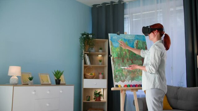 modern hobby, young woman in vair glasses uses modern technology and draws a picture using paints and brushes while viewing virtual reality while standing in room