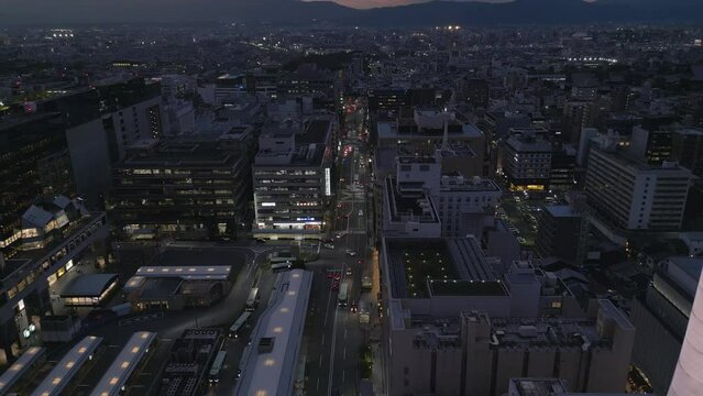 dusk aerial view of Kyoto flying back revealing illuminated Kyoto Tower