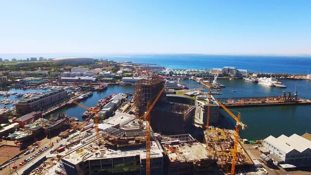 Construction, drone and industrial city with ocean for holiday or vacation location with buildings and cityscape. Sky, aerial view and downtown urban apartment by sea, shore or harbor in Cape Town.