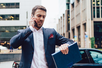 Displeased businessman answering phone call and checking time
