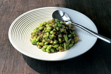 fried edamame and pickled cabbage in a white plate
