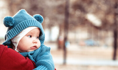 Cute little newborn baby in his mom's arms in the park. Autumn season