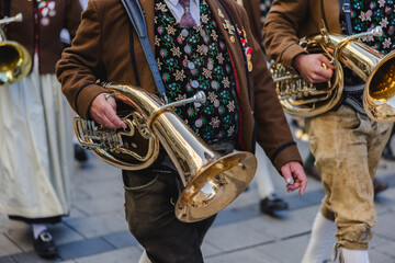 A man in traditional Bavarian attire carrying a wind instrument as part of a traditional brass band