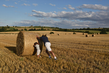 Kid playing with hay bales in the field