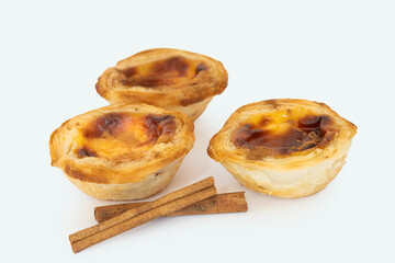 Pastel de nata or pastel de belem from Portugal. Three tart desserts on white background with a top view. Accompanied by two cane sticks as decoration.
