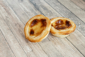 Pastel de nata or pastel de belem from Portugal, two pastries on a wooden table, one on top of the other.