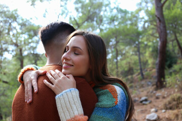 Young couple hiking in the woods. Hipster boyfriend and girlfriend hugging under the tree. Close up, copy space, forest background.
