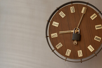 Old clock with Roman numerals on the dial with a padlock on the hands. Start of work time