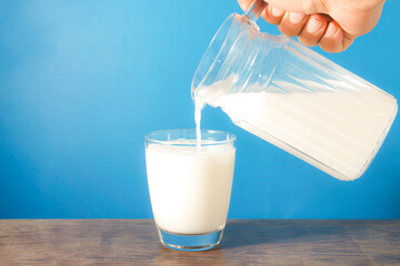 Pour the milk from the jar into the glass.
