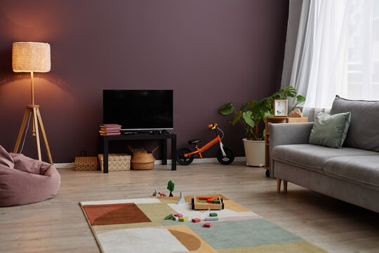 Background image of cozy living room interior with maroon wall and childrens toys scattered on carpet, copy space