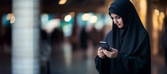Foto op Canvas Muslim woman in black abaya with smartphone. AI generated. © serperm73