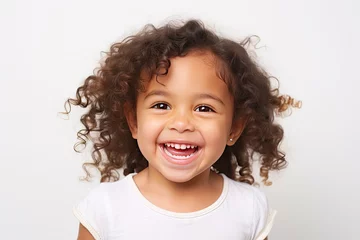 Fotobehang Curly-haired child displaying bright smile against light background. Child portraits and expressions. © Postproduction