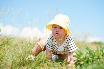 Cute baby child in panama is sitting in a field with dry grass and blue sky