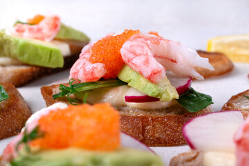 Bruschetta with shrimp, caviar, avocado, radish and cheese. Close-up
