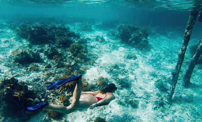 Travel woman diving into crystal blue ocean with beautiful coral reef for exploring tropical underwater