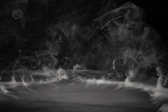 Smoke, fog or steam on black background flowing or rolling from center to edges