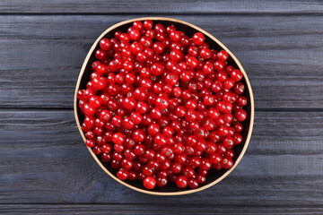 Ripe red currants in bowl on wooden rustic table, top view