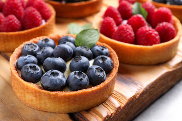 Tartlet with fresh blueberries on wooden board, closeup. Delicious dessert