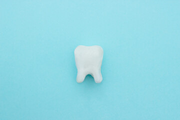 White tooth on blue background with copy space, close-up.