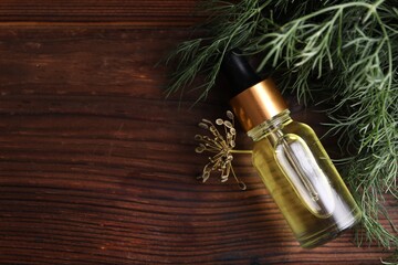 Fototapeta premium Bottle of essential oil and fresh dill on wooden table, flat lay. Space for text