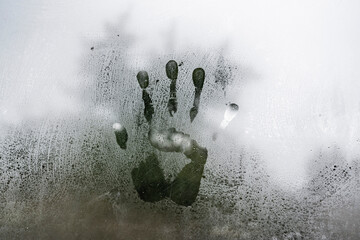 The imprint of a child's palm on a foggy window, glass.