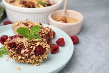 Tasty baked oatmeal with raspberries on light grey table, closeup. Space for text