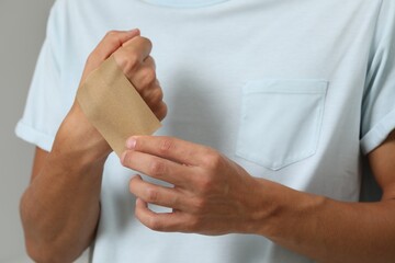 Man putting sticking plaster onto hand, closeup