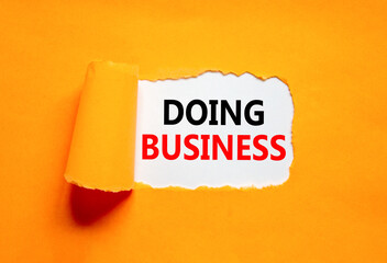 Doing business symbol. Concept words Doing business on beautiful white paper. Beautiful orange table orange background. Business, motivational Doing business concept. Copy space.