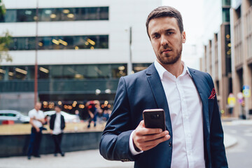 Serious manager using smartphone near road