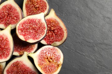 Halves of fresh ripe figs on grey textured table, flat lay. Space for text