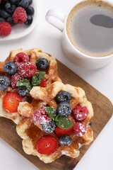 Delicious Belgian waffles with fresh berries on white table, flat lay
