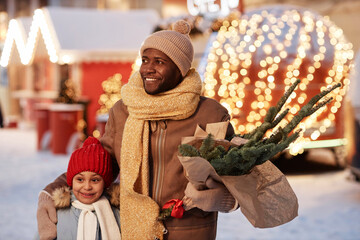 Waist up portrait of happy African American father and daughter enjoying Christmas shopping outdoors in winter market