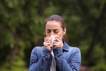 Woman suffering from seasonal spring allergy outdoors