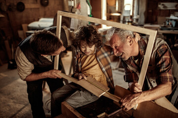 Multigenerational family of male carpenters teaching their youngest one the ways in a carpentry shop