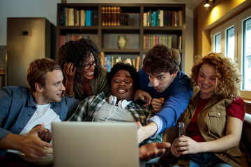 Young and diverse group of friends watching a movie together on the laptop at home