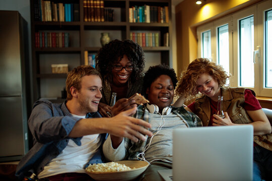 Young and diverse group of friends watching a movie together on the laptop at home - Powered by Adobe