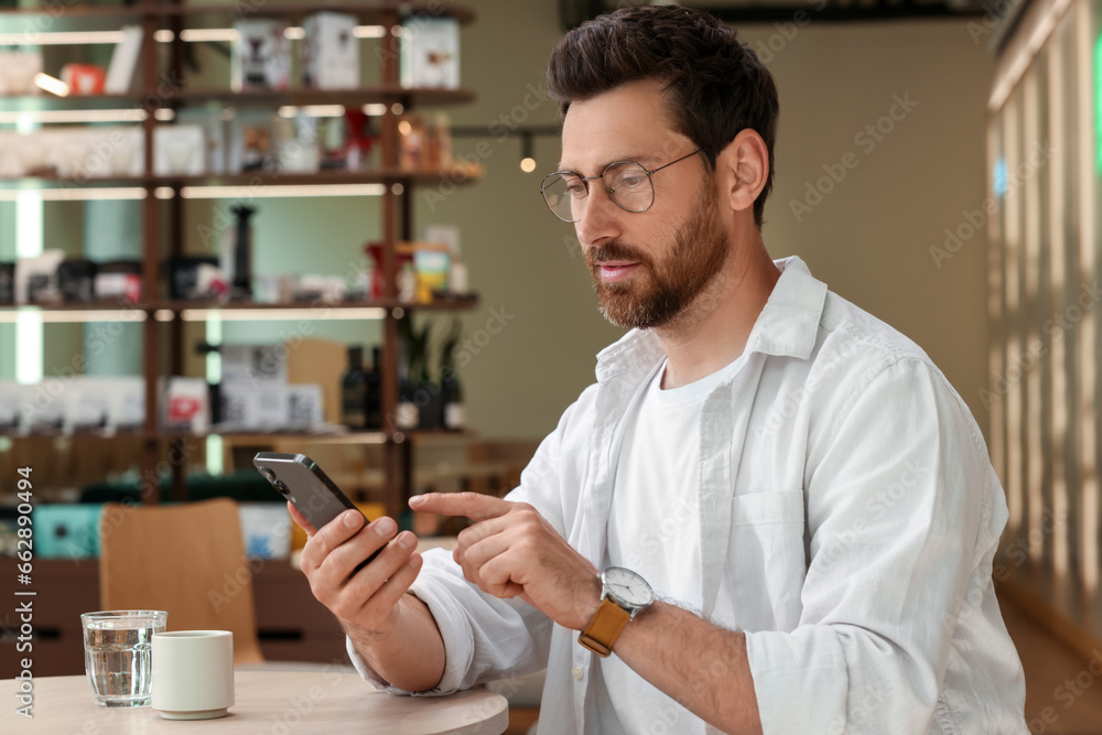 Aufkleber handsome man sending message via smartphone at table indoors