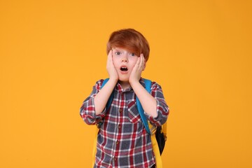 Portrait of emotional schoolboy on orange background