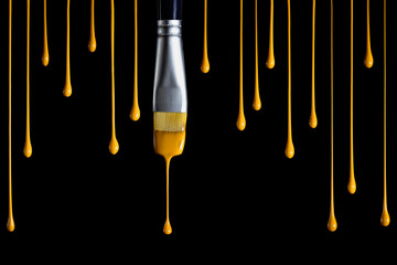 Paintbrush dripping yellow paint isolated over black