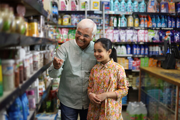 Happy Grandpa and Granddaughter enjoying purchasing in a grocery store. Buying grocery for home in a supermarket.