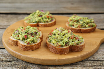 Slices of bread with tasty guacamole on wooden table, closeup