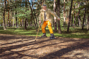 Funny old man is roller skating in the park. An active grandfather with a walking stick dances and makes faces. Grandfather with a white beard.