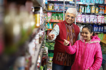 Happy Grandpa and Granddaughter enjoying purchasing in a grocery store. Buying grocery for home in a supermarket.