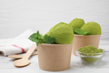 Paper cups with tasty matcha ice cream on white wooden table, closeup