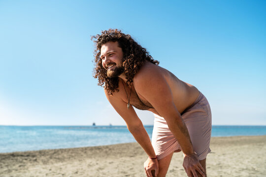 Cheerful curly man relaxing on the beach during sunny summer day