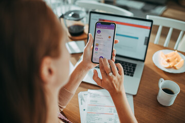 Young woman checking her profile on a bank app while paying bills at home