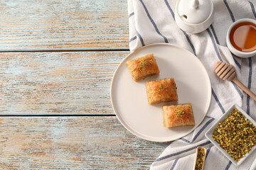Delicious sweet baklava with nuts and honey on light blue wooden table, flat lay. Space for text